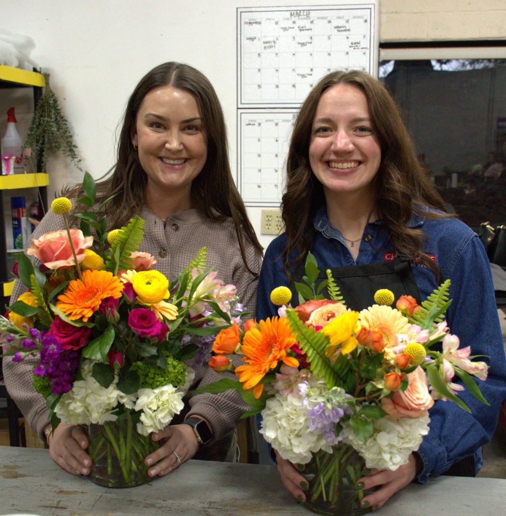 Two of Chesapeake's associates posing with their floral arrangements during the Women in Construction Week event.